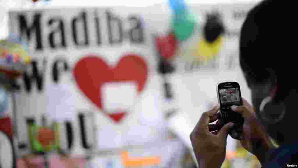 A woman takes a photograph outside the hospital where ailing former President Mandela is being treated.