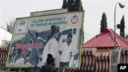 A police officer takes a break under an election billboard in front of the Independent National Electoral Commission office in Abuja, Mar 17 2011