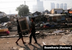 Penghuni liar membawa kulkas mereka ke tempat lain saat petugas keamanan dari PT Kereta Api Indonesia (PT KAI) membongkar rumah-rumah ilegal yang dibangun di sepanjang rel kereta api di Tanah Abang di Jakarta 8 Agustus 2014. (Foto: REUTERS/Beawiharta)