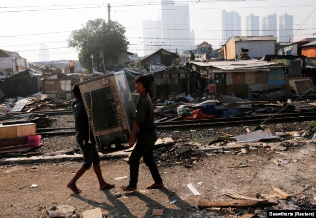 Penghuni liar membawa kulkas mereka ke tempat lain saat petugas keamanan dari PT Kereta Api Indonesia (PT KAI) membongkar rumah-rumah ilegal yang dibangun di sepanjang rel kereta api di Tanah Abang di Jakarta 8 Agustus 2014. (Foto: REUTERS/Beawiharta)