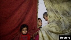 Anak-anak berdiri dekat tirai-tirai di sebuah tempat perlindungan di Douma, sebuah kota yang terkepung di timur Ghouta, di Damaskus, Suriah, 11 Maret 2018. 