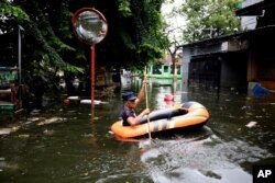 A man navigates an inflatable boat at a flooded neighborhood in Jakarta, Indonesia, Jan. 4, 2020.