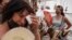 FILE - Women cool themselves with fans in the Rastro flea market during a heatwave in Madrid, Spain, Aug. 15, 2021. (AP Photo/Andrea Comas, file)