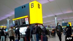 Los viajeros hacen cola con sus equipajes en la sala de salidas de la Terminal 2 del aeropuerto de Heathrow en el oeste de Londres, el 21 de diciembre de 2020.