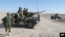 Afghan National Army soldiers stand guard at a checkpoint on the way to the Sangin district of Helmand province, Afghanistan, Dec. 23, 2015.