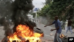 A Haitian throws a tire into fire during a protest following presidential elections in Port-au-Prince, 8 Dec 2010
