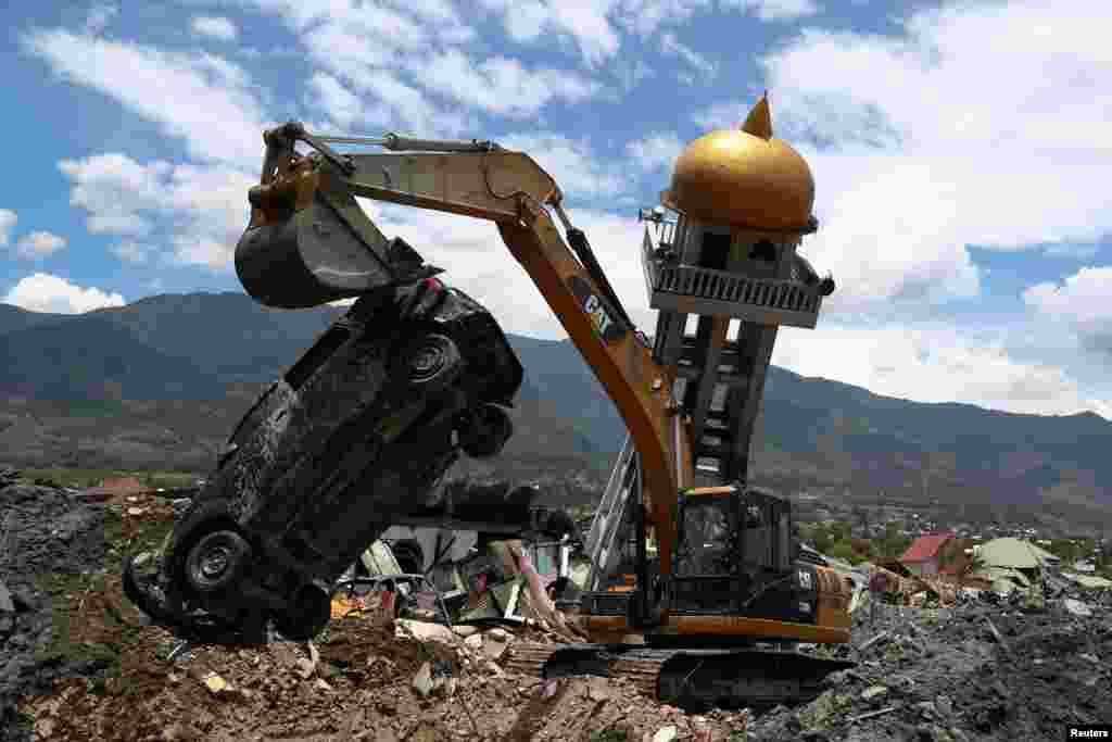 An excavator removes a damaged car next to the debris of a mosque damaged by an earthquake in the Balaroa neighbourhood in Palu, Central Sulawesi, Indonesia.