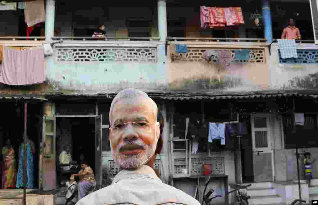 Seorang pendukung partai oposisi utama Bharatiya Janata memakai masker wajah kandidat perdana menteri Narendra Modi, pada kampanye di Mumbai (9/4). (AP/Rajanish Kakade)
