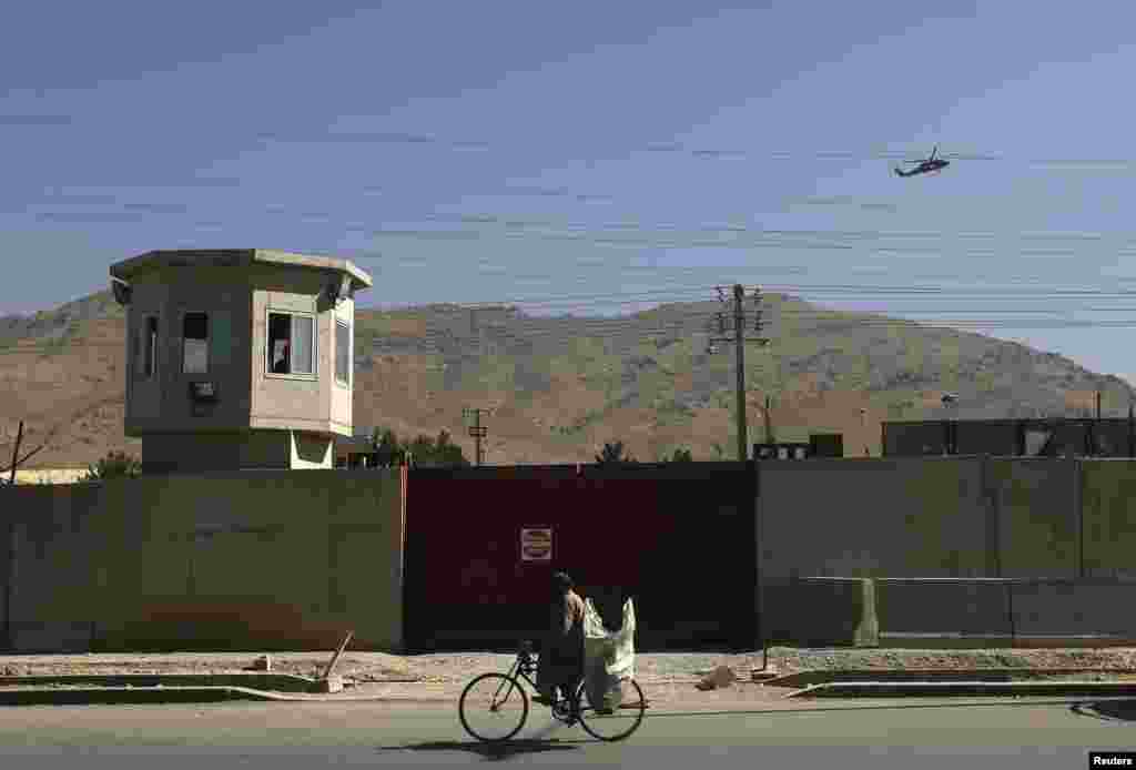 A NATO helicopter flies overhead at the site of a suicide attack outside the counter-narcotics office near the Kabul International Airport, July 22, 2014.