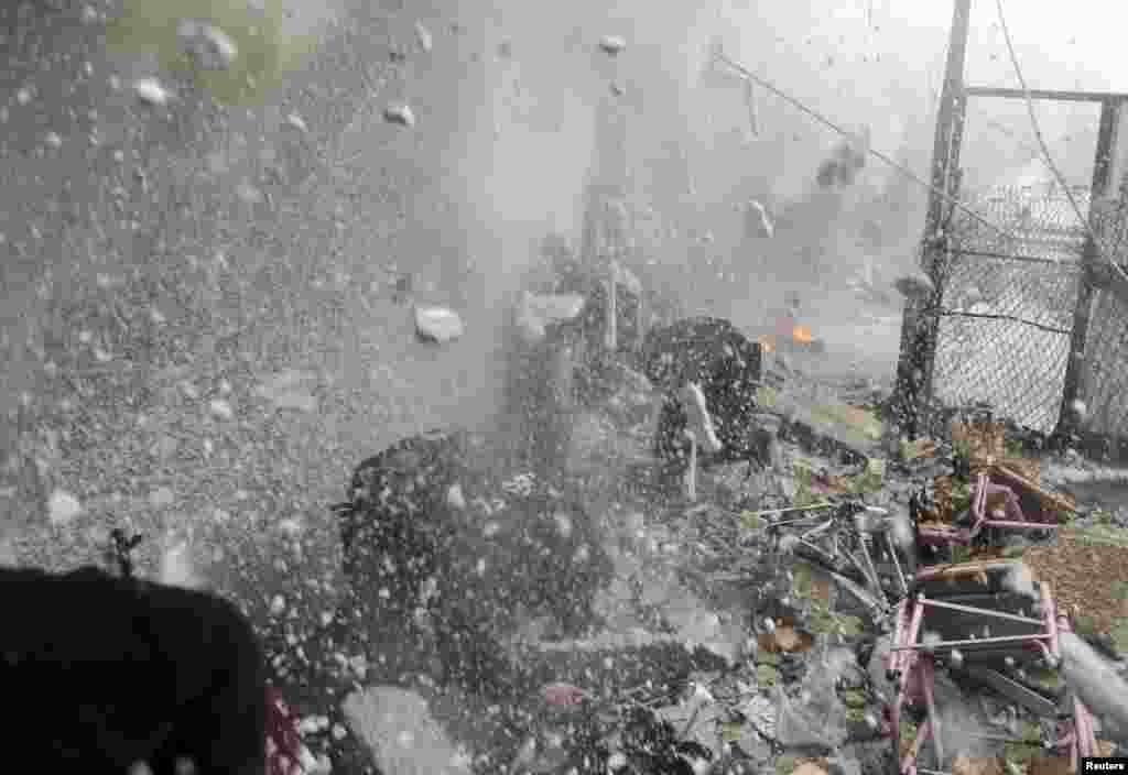 Free Syrian Army fighters run for cover as a tank shell explodes on a wall during heavy fighting in the Ain Tarma neighborhood of Damascus, Syria. 