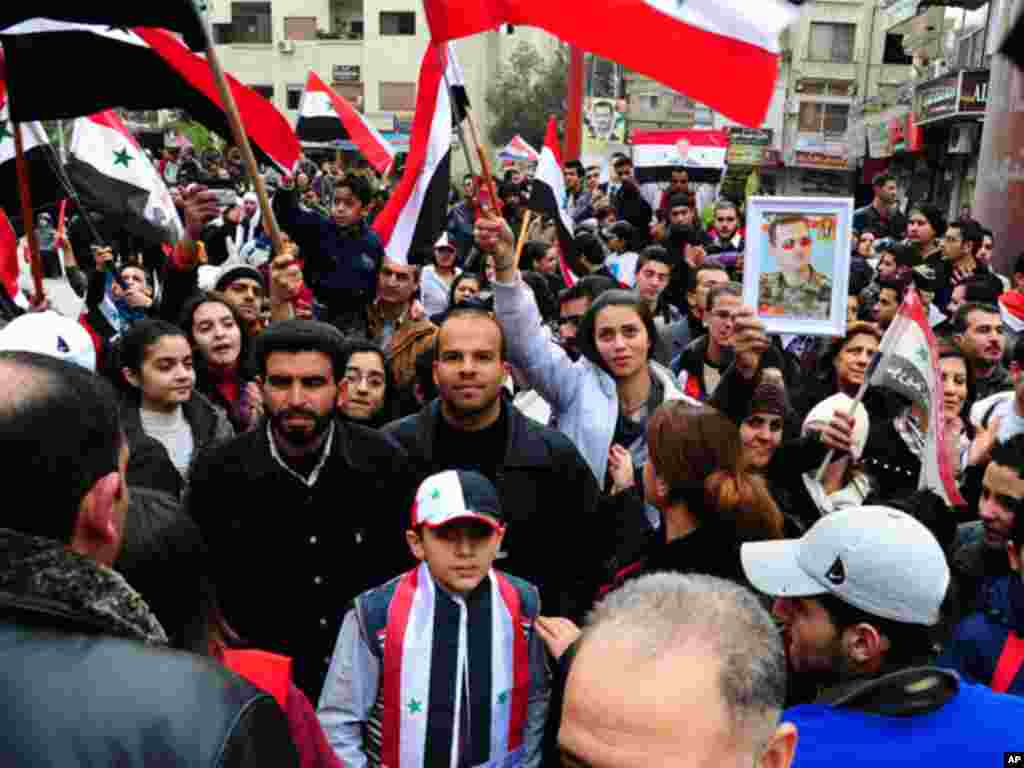 Supporters of Syria's President Bashar al-Assad wave Syrian flags and carry pictures of him as they write on what they said is the world's longest letter, in Damascus on January 15, 2012. (Reuters)