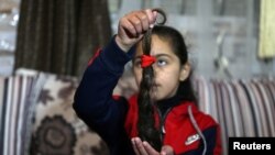 Palestinian cancer patient Tala Al-Mabhouh, 11, who had a bone marrow transplant, shows a part of her hair which she lost due to chemotherapy, in Rafah in the southern Gaza Strip, Feb. 2, 2021.
