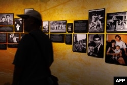 Seorang pengunjung berjalan menyaksikan pameran foto Bruce Lee di Museum Warisan Hong Kong di Hong Kong, 15 Juli 2023, menjelang peringatan 50 tahun kematian bintang seni bela diri tersebut yang jatuh pada tanggah 20 Juli 2023. (May JAMES / AFP)