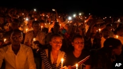 FILE - In this April 7, 2019 file photo, people attend a candlelit vigil during a memorial service marking 25 years since the genocide, at Amahoro stadium in the capital Kigali, Rwanda.