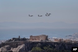 A formation of Greek fighter jets flies over the temple of the Parthenon, on the ancient Acropolis hill during a military parade in Athens March 25, 2017.