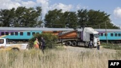 Les travailleurs des services d'urgence se tiennent près du site où un train est en collision avec un camion, à Kroonstad, province de Free State, le 4 janvier 2018