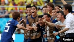 Japan's Yuya Osako celebrates scoring their second goal with coach Akira Nishino and teammates.