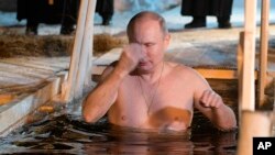 Russian President Vladimir Putin crosses himself as he bathes in ice-cold water on Epiphany near St. Nilus Stolobensky Monastery on Lake Seliger, Svetlitsa village, Russia, Jan. 19, 2018. 