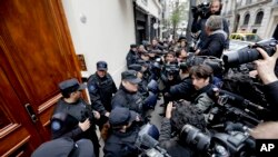 Police keep the press at bay as they execute a search warrant at the home of Senator and Former President Cristina Fernandez, in Buenos Aires, Argentina, Aug. 23, 2018.