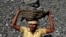 FILE - an Indian daily wage laborer carries a basket on his head filled with chunks of coal at a local coal depot on the outskirts of Cuttack, India, Nov. 13, 2014. 