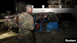 A Somali policeman looks at the wreckage of a vehicle destroyed by a car bomb at the Banadir beach restaurant at Lido beach in Somalia's capital, Mogadishu, Aug. 25, 2016. 