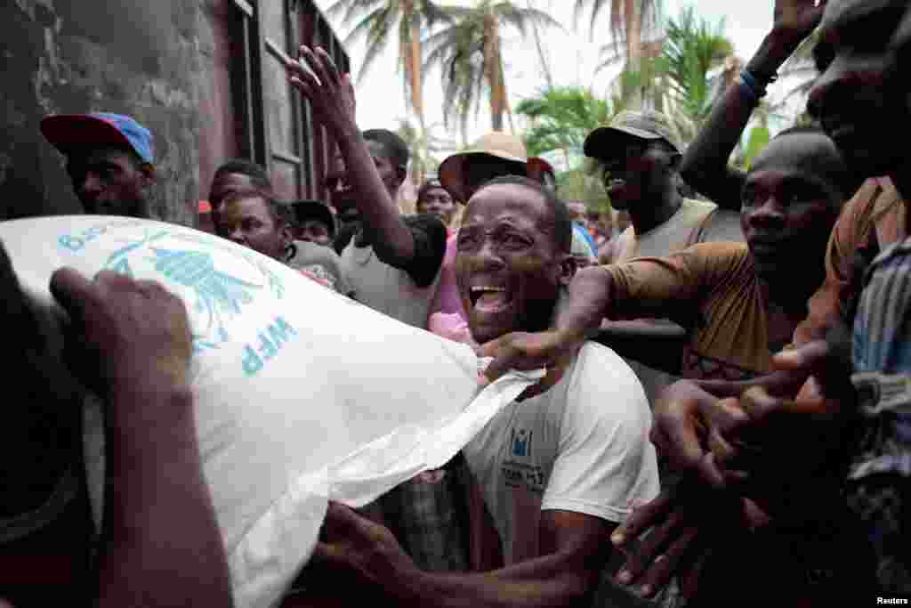 Residents try to get a sack of rice, after a distribution was rescheduled and food stored, following Hurricane Matthew in Saint Jean du Sud, Haiti.