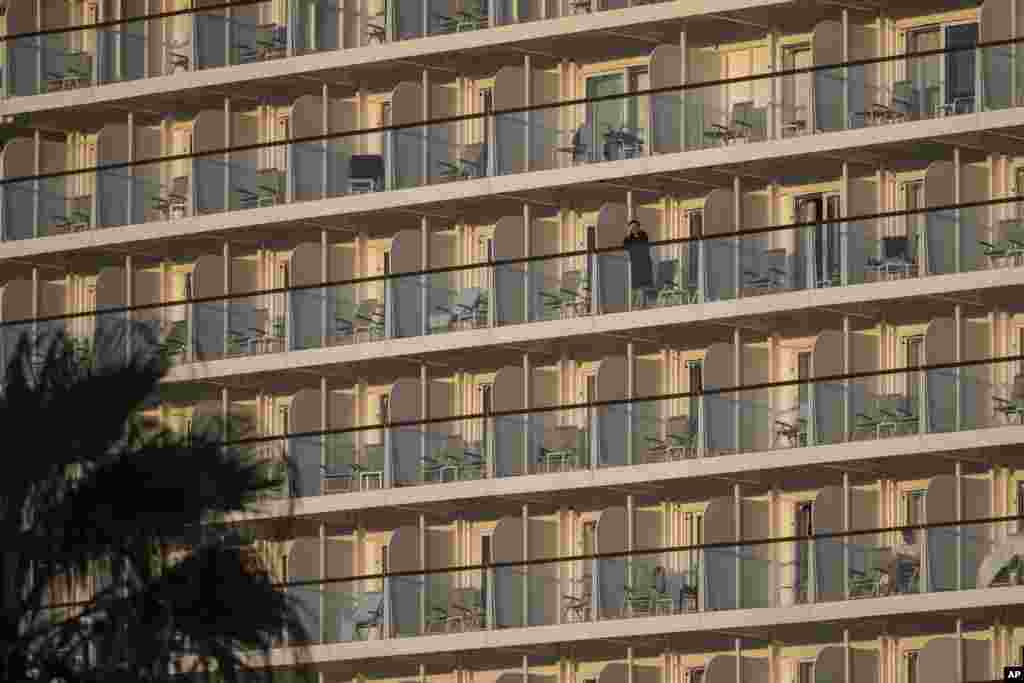 A passenger of the Mein Schiff 6 cruise ship stands outside her cabin as the ship is docked at Piraeus port, near Athens, Greece.