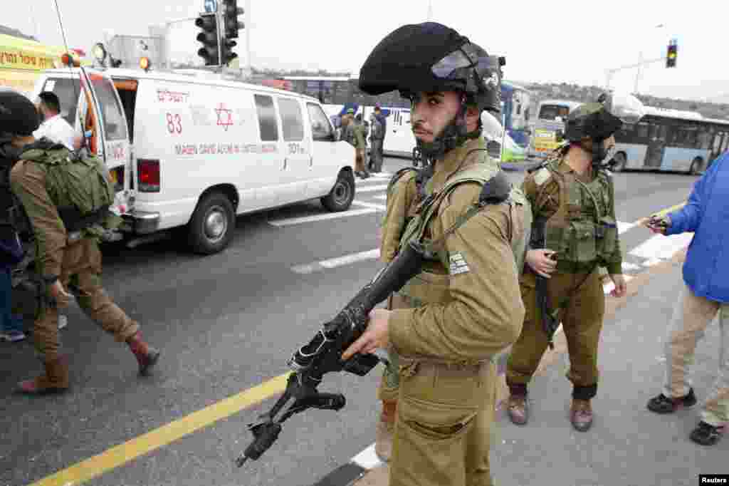 Soldiers stand at the scene where a Palestinian attacked civilians with a chemical substance near the settlement of Neve Daniel, Dec. 12, 2014. 