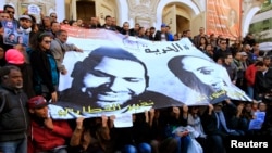 FILE - People hold a poster of journalists Nadhir Ktari (L, in poster) and Sofian Chourabi, who went missing in Libya in September, during a rally over their disappearance, in Tunis, Jan. 9, 2015.