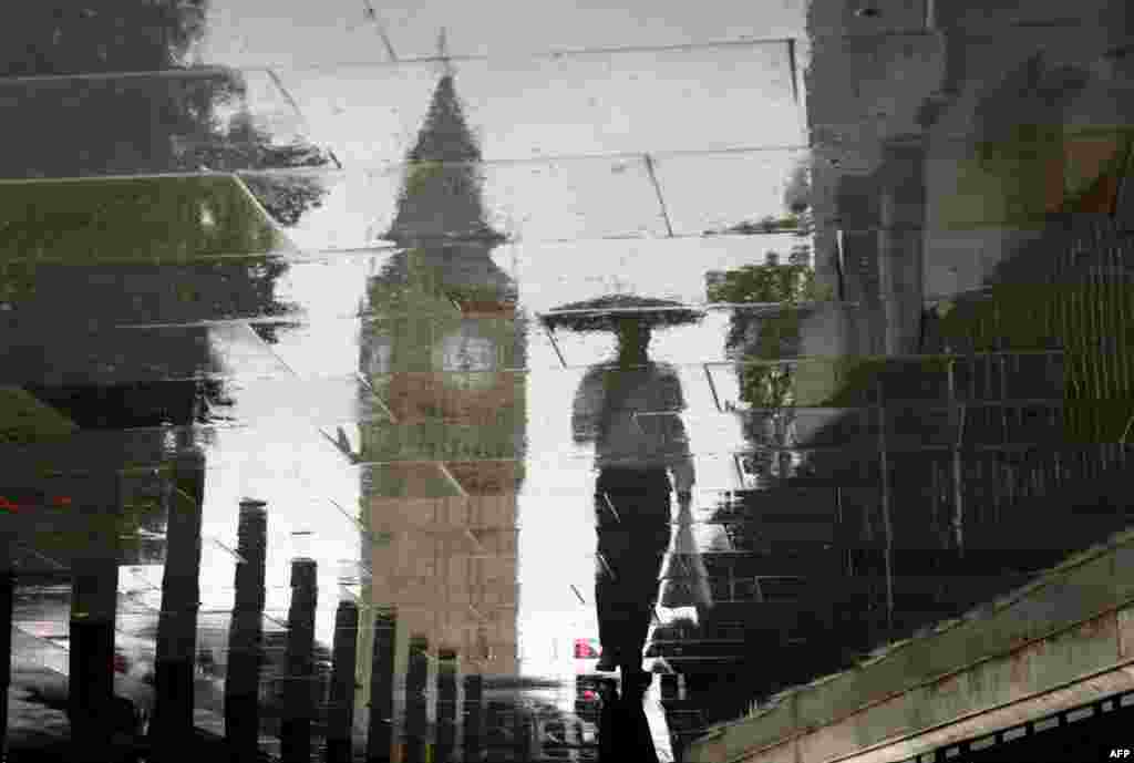 4 tháng 8: Bóng một người phản chiếu bên cạnh tháp đồng hồ Big Ben trong một ngày mưa ở London. REUTERS/Stefan Wermuth