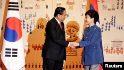 Presiden Laos Choummaly Sayasone (kiri) berjabat tangan dengan Presiden Korea Selatan Park Geun-hye saat tiba di Istana Presiden di Seoul (22/11). (Reuters/Lee Jin-man/Pool)