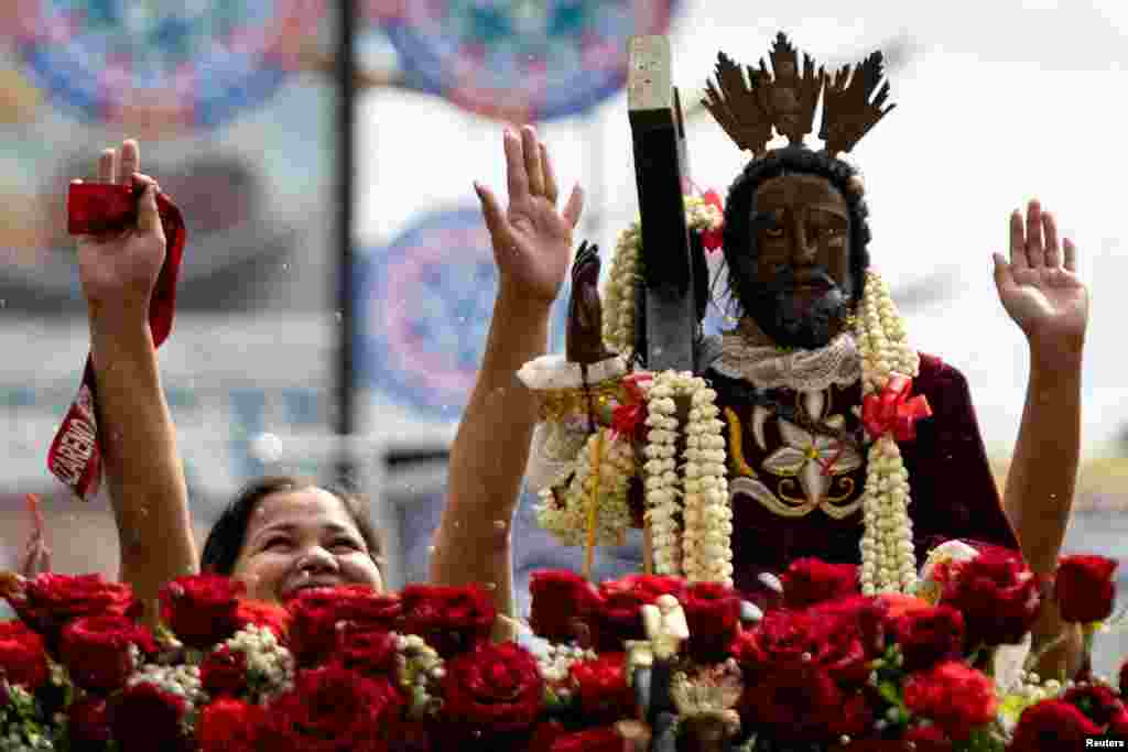 Filipino Catholic devotees raise their hands to be blessed with holy water during the parade of Black Nazarene replicas ahead of its feast day, in Quiapo, Manila, Philippines.