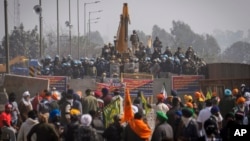 Protesting farmers stand across a police barricade near Shambhu border that divides northern Punjab and Haryana states, some 200 kilometers (120 miles) from New Delhi, India, Wednesday, Feb.21, 2024.