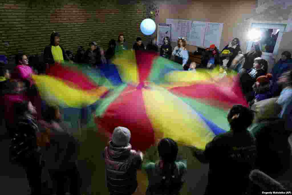 Niños y voluntarios de la ONG Ukrainian Frontiers agitan un paracaídas de juguete durante las celebraciones del Día de San Nicolás en Izium.&nbsp;