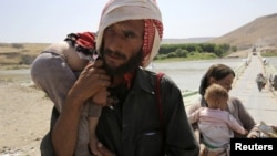 A man and his wife from the minority Yazidi sect, fleeing the violence in the Iraqi town of Sinjar, carry their children as they re-enter Iraq from Syria at the Iraqi-Syrian border crossing in Fishkhabour, Dohuk province, August 14, 2014.