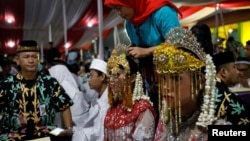 A bride's headdress is adjusted as she takes part in a mass wedding organized by the city government as part of New Year's Eve celebrations in Jakarta, Indonesia, December 31, 2017.