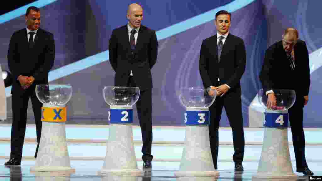 Former England soccer player Geoff Hurst (R) draws a ball from a pot as former Brazil player Cafu (L), former France player Zinedine Zidane (2nd L) and former Italy player Fabio Cannavaro look on during the draw for the 2014 World Cup.