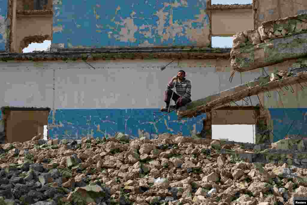 A displaced man sits on the ruins of a destroyed building outside Hammam al-Alil camp, south of Mosul, Iraq.