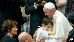 Le pape François embrasse un enfant lors d’une audience spéciale avec les personnes handicapées dans la salle Paul VI au Vatican, 11 juin 2016. 