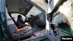 An Afghan policeman inspects the interior of a car belonging to the chief of police of Nimroz province, that was hit by a roadside bomb, in the Hadraskan district of Herat province, December 10, 2012.