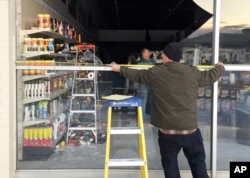 Dennis Keeling measures for a broken window at an auto parts store in Anchorage, on Nov. 30, 2018.