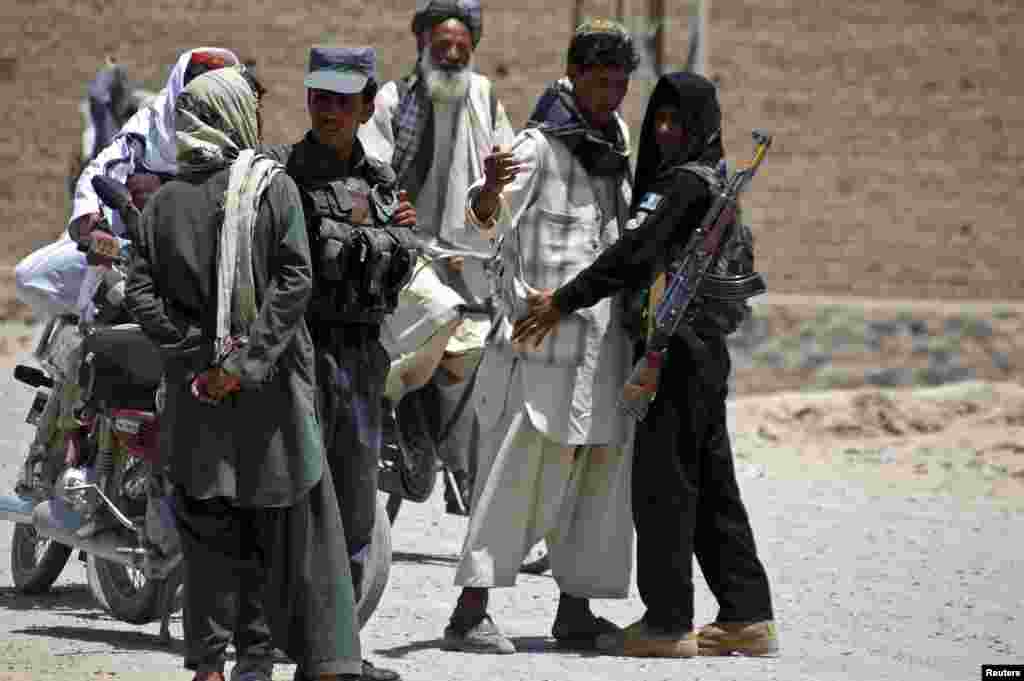 Afghan policemen search people near the house belonging to Afghan President Hamid Karzai&#39;s cousin, Hashmat Karzai, at the site of a suicide attack, in Kandahar, July 29, 2014.