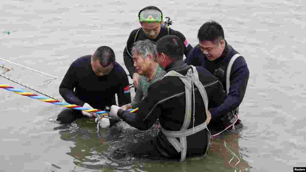 Une femme est secourue par des plongeurs qui la sortent du bateau qui a fait naufrage à Jianli, dans la province de Hubei, Chine, le 2 juin.