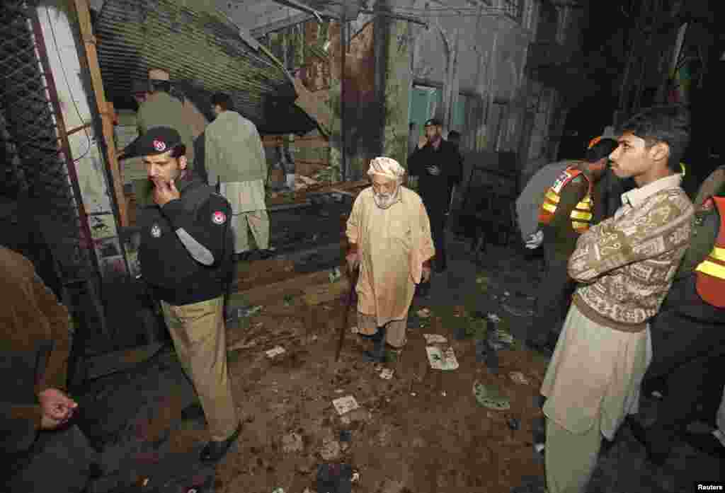 پولیس اہلکار اور امدادی کارکن دھماکے کی جگہ پر کھڑے ہیں