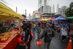 Para pengunjung bazaar mengenakan masker saat belanja makanan menjelang buka puasa di bulan suci Ramadan, di tengah pandemi COVID-19, di Kuala Lumpur, Malaysia, 15 April 2021. (REUTERS/Lim Huey Teng)