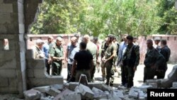 Army soldiers inspect the site of a suicide attack at a bus station in the government-held city of Hama in western Syria, in this handout picture provided by SANA on July 6, 2017, Syria.