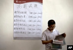 FILE - Chinese man reads the employment newsletters at a job fair held at the China International Exhibition Center in Beijing.