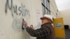 Архив: доброволец закрашивает оскорбительные для мусульман надписи на стене мечети в городе Роузвилл, штат Калифорния