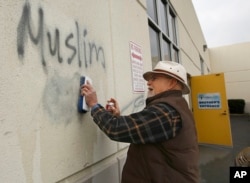 FILE - Graffiti are cleaned off the side of a mosque after what officials called the commission of a hate crime, Feb. 1, 2017, in Roseville, Calif. The Tarbiya Institute was spray-painted with a dozen obscene and racist slurs.