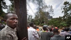 Onlookers observe from an overlooking hill as a plume of black smoke billows over the Westgate Mall, following large explosions and heavy gunfire, in Nairobi, Kenya, Sept. 23, 2013. 